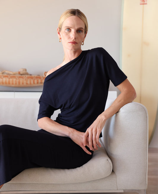 Woman in black dress sitting on couch.